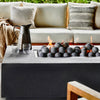 Concrete fire pit table lit in a backyard seating area