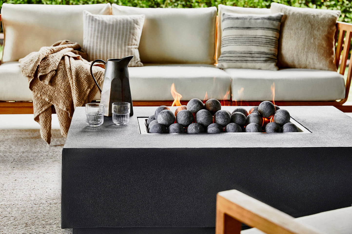 Concrete fire pit table lit in a backyard seating area