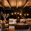 Couple sitting beside the lit concrete fire pit table at night
