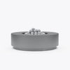 Round concrete fire pit table in gray finish with lava rocks, front view