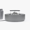 Round gray concrete fire pit table with grill grate and lava rocks, connected to a propane tank