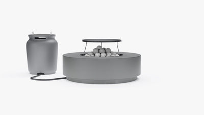Round gray concrete fire pit table with grill grate and lava rocks, connected to a propane tank