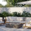 OuterStone fire pit table lit beside outdoor seating with striped cushions