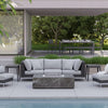 OuterStone fire pit table set among black wicker seating and side tables in a garden