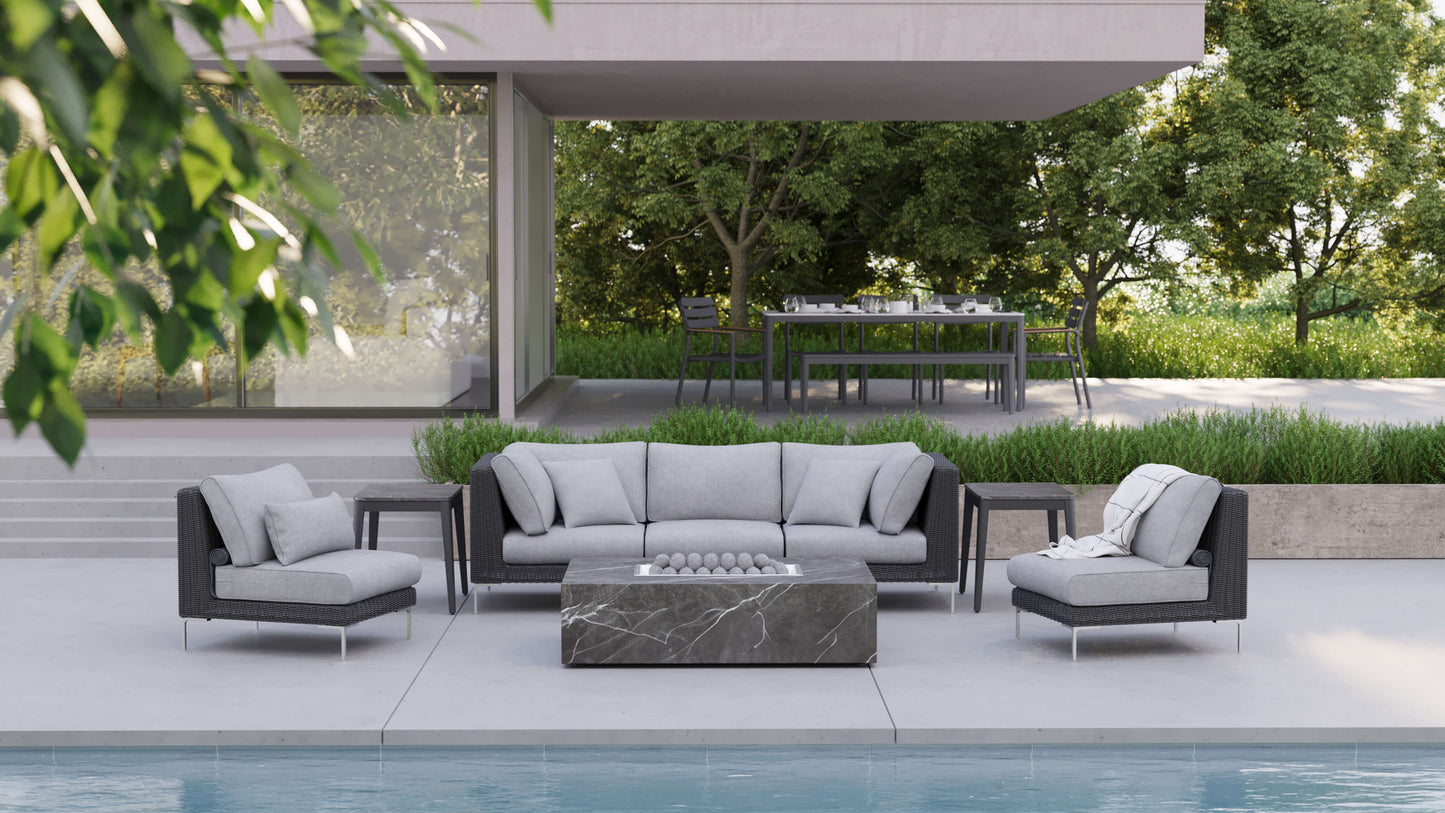 OuterStone fire pit table set among black wicker seating and side tables in a garden