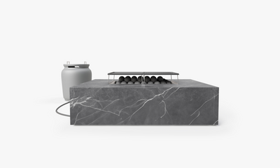 Rectangular OuterStone fire pit table in gray marbled stone with lit flame, shown with matching propane tank cover