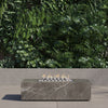 OuterStone rectangular fire pit table lit on a patio at dusk