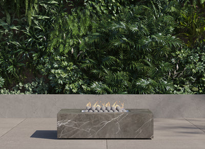 OuterStone rectangular fire pit table lit on a patio at dusk