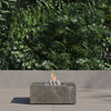 Square OuterStone fire pit table lit on a patio at dusk