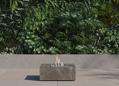 Square OuterStone fire pit table lit on a patio at dusk