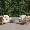 Round concrete fire pit table lit in a garden seating area at dusk