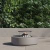 Round concrete fire pit table with the griddle fitted over the lit burner